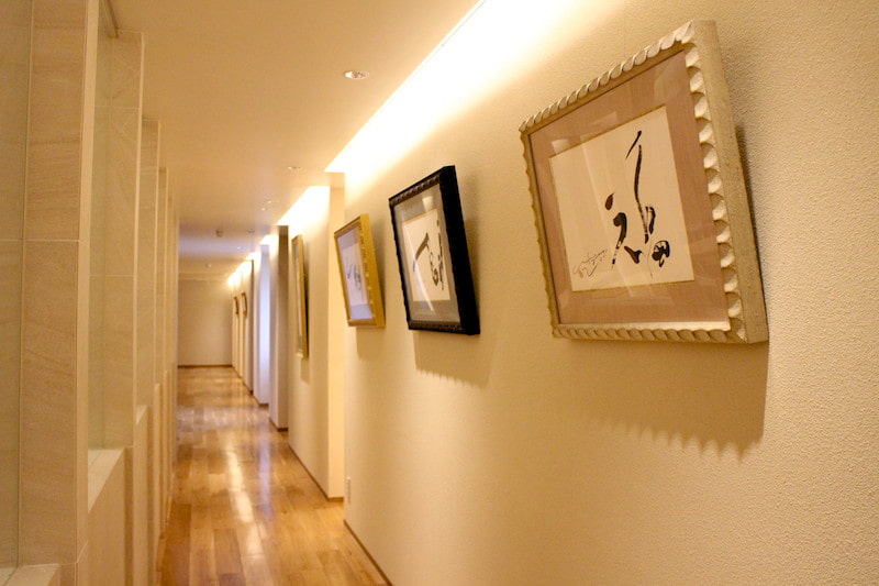 A warm, wood-filled employee cafeteria with calligraphy art displayed like a gallery along the corridor.